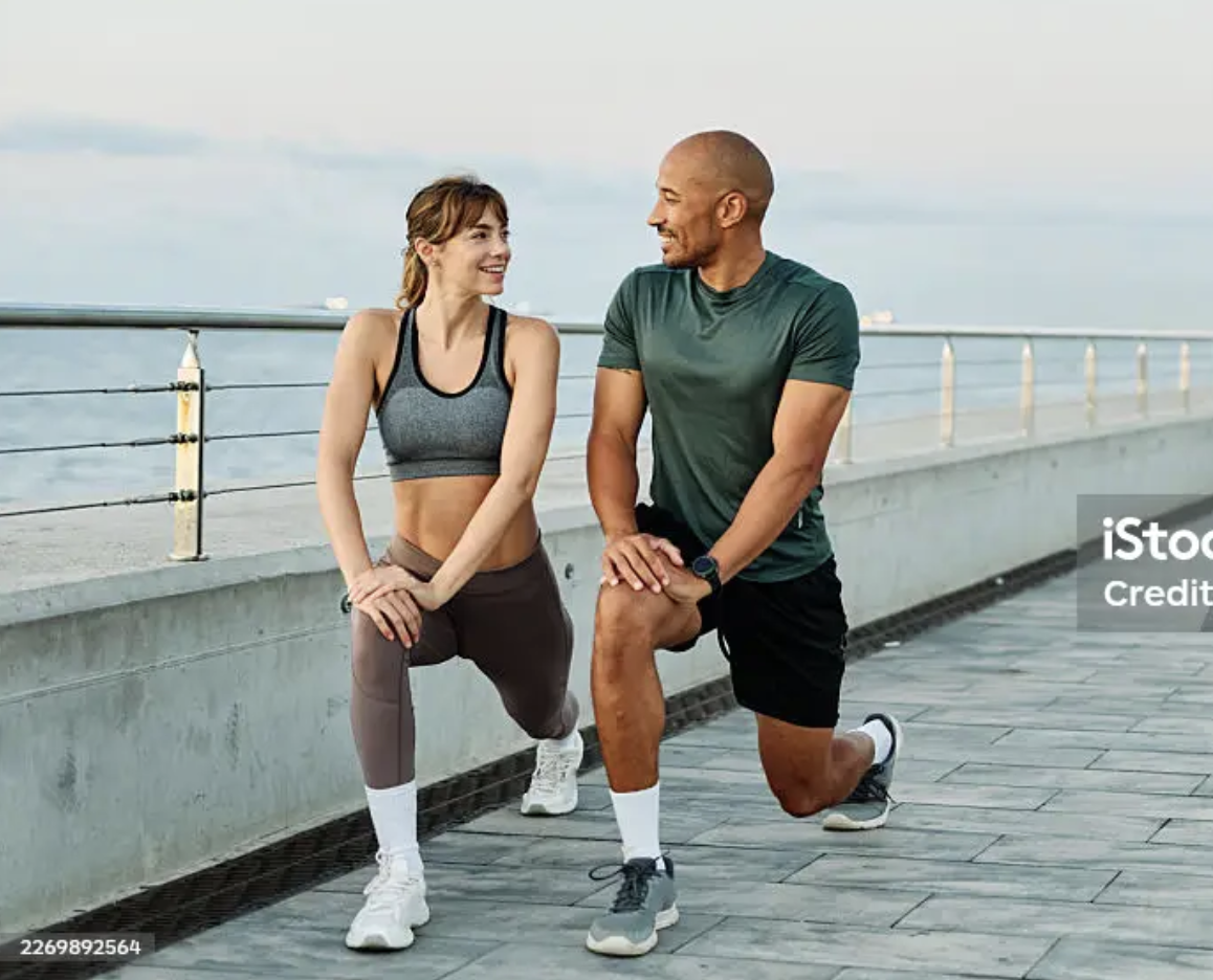 Two people exercising together by the water