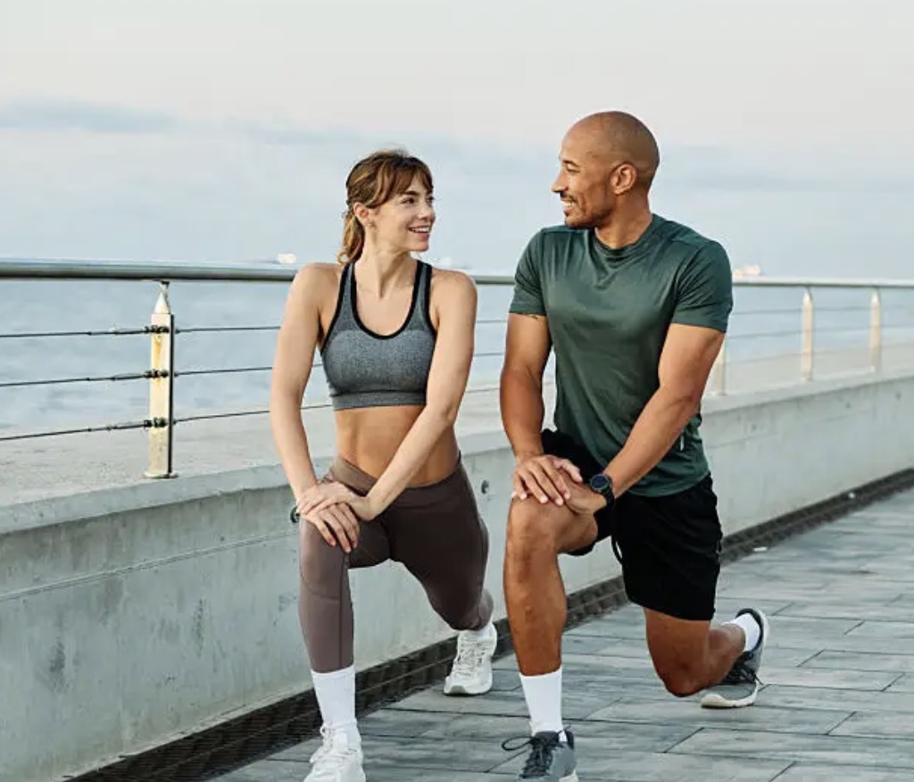 Two people exercising together by the water